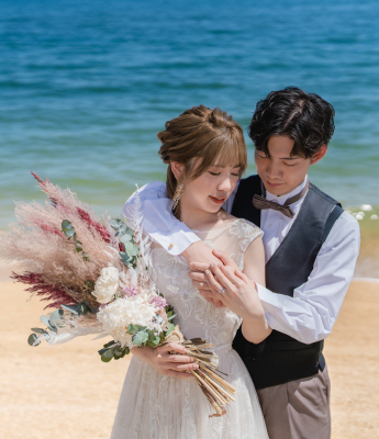 海辺で抱き合うドレスとタキシードの二人