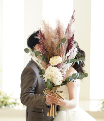 ブーケで顔を隠す新郎新婦